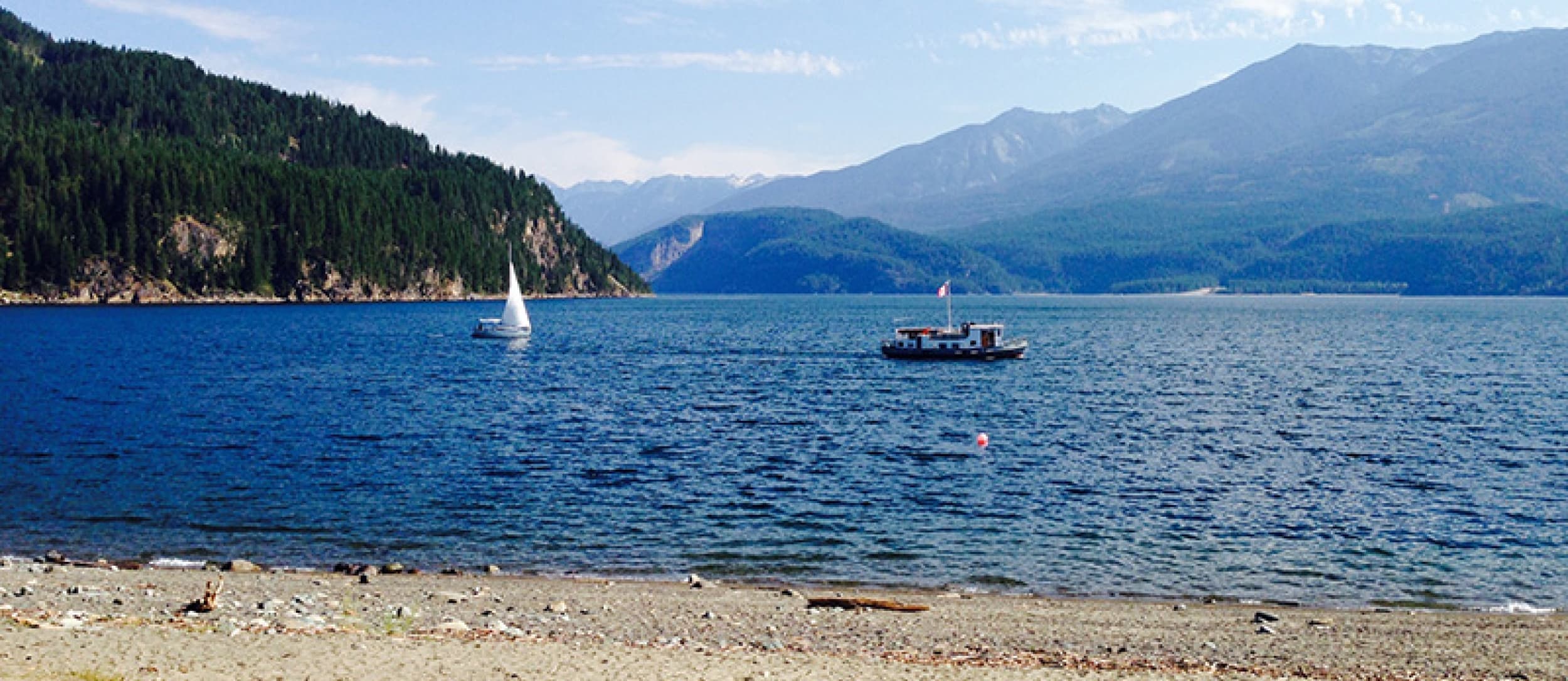 Boats on Kootenay Lake off a quiet beach