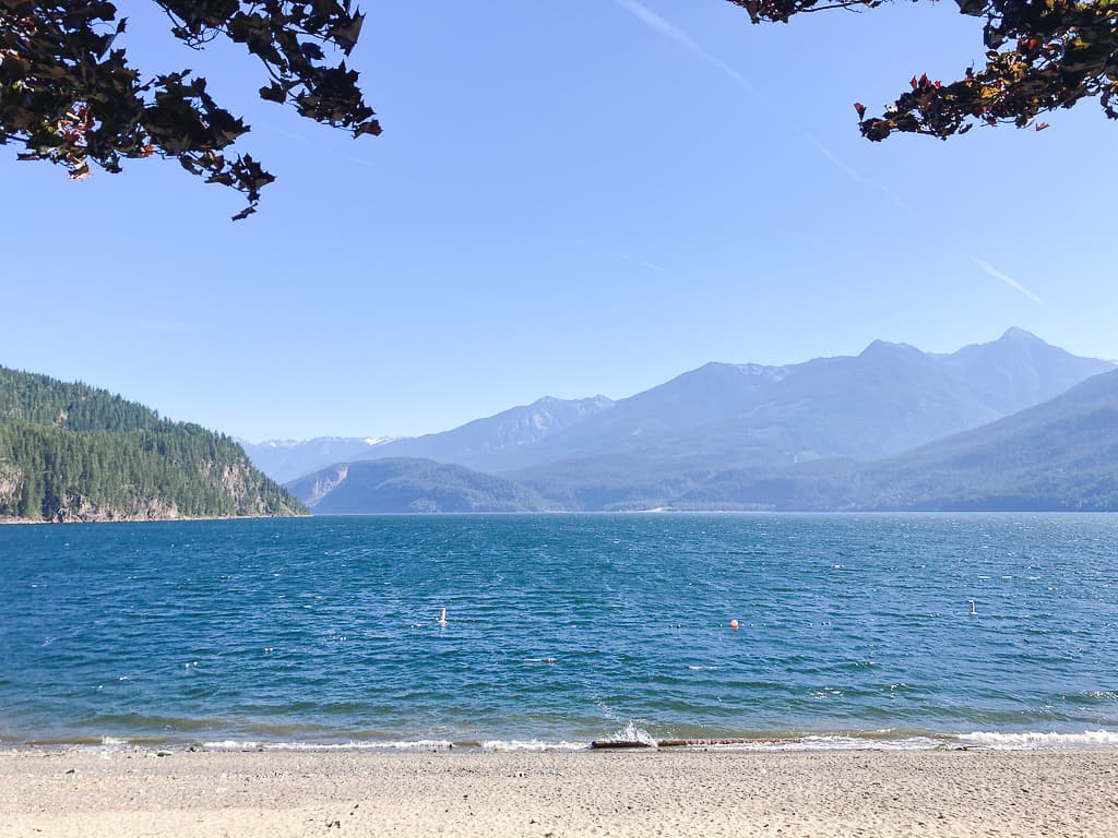 Sandy beach on Kootenay Lake with mountains across the water