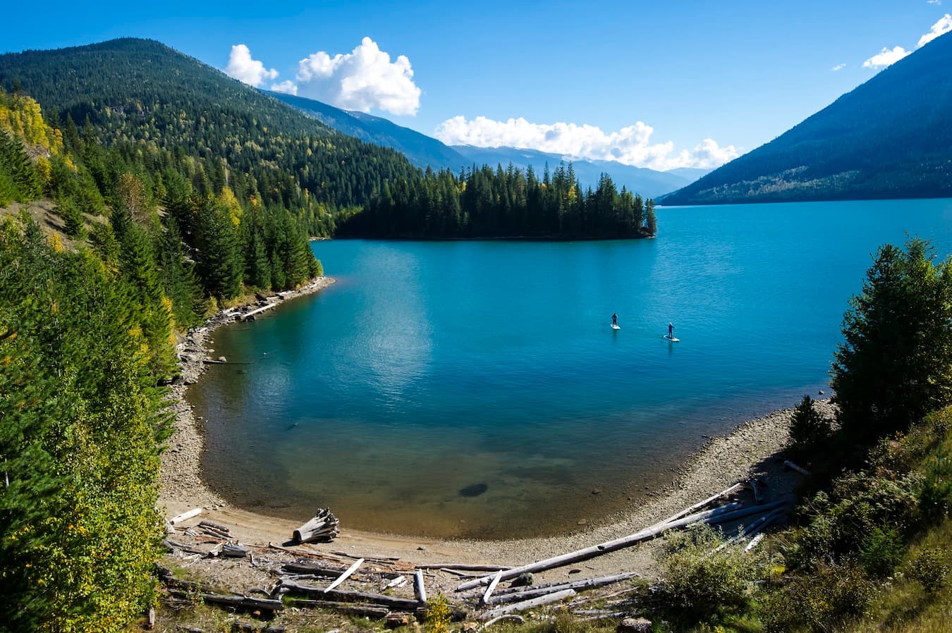 Turquoise cove on a Kootenay lake ringed by forest and mountains